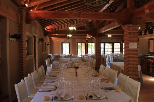 a long dining room with white tables and white chairs at Hotel Venta Magullo in La Lastrilla