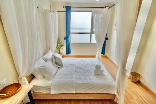 a bedroom with a white bed with a window at Mian Sapphire Home toà S1 S2 in Ha Long