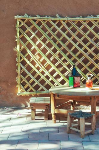 a table and benches in a room with a latticeaged wall at Dar Sofar in Agdz