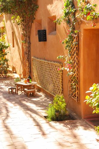a patio with a table and a bench next to a building at Dar Sofar in Agdz