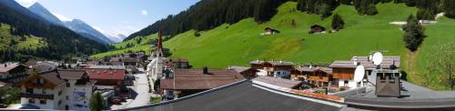 a small town with a green hill and houses at Pension Bergkristall in Tux