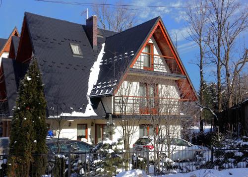 a house with a black roof in the snow at Gościniec w Zakopanem in Zakopane
