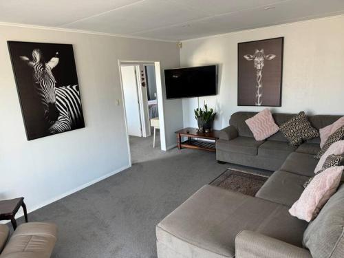 a living room with a couch and a zebra picture on the wall at Great House - Family Fun in Napier