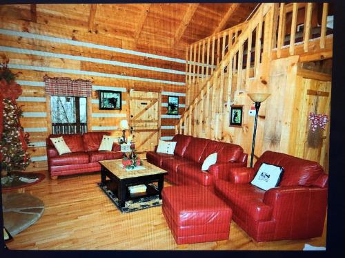 a living room with red leather furniture and a christmas tree at Mountain Hideaway in Pigeon Forge