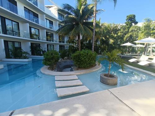a swimming pool with palm trees and a building at luxury central park lagunas in Tulum