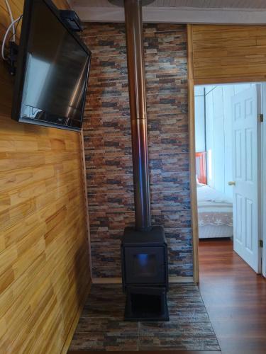 a fireplace in a living room with a tv on a brick wall at Cabañas Mirador del Puma in Hornopiren