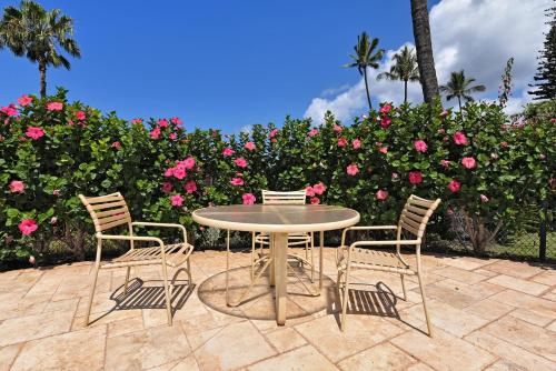 a table and four chairs in front of pink roses at International Colony Club 37 · ICC 37 Remodeled Hawaiian Cottage in Kaanapali
