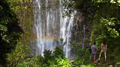 two people standing in front of a waterfall with a rainbow at International Colony Club 37 · ICC 37 Remodeled Hawaiian Cottage in Kaanapali