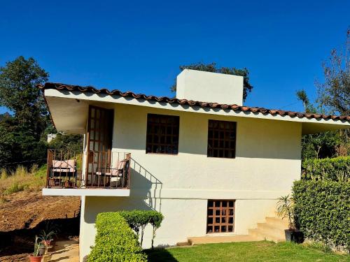 a white house with a porch and a balcony at La Cabaña Zacatlán2 in Zacatlán