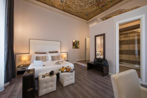 um quarto com uma grande cama branca e 2 cadeiras em Arenula Suites em Roma