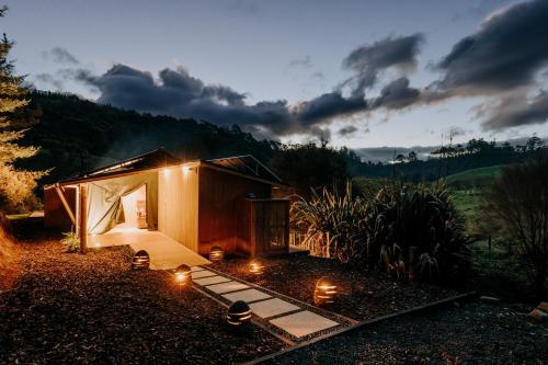 a small house with lights in the yard at Jungle Den in Tauranga