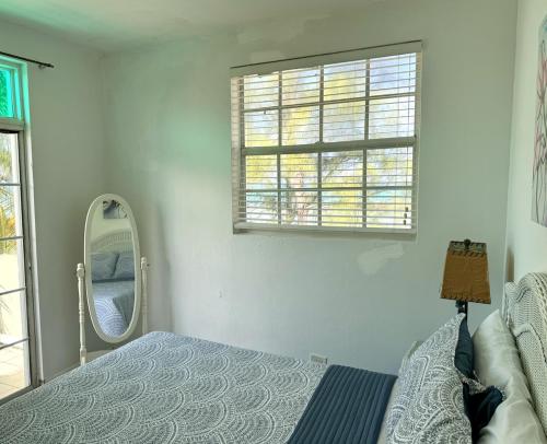 a bedroom with a bed and a mirror and a window at Sunset Cove - Vacation In Paradise! in Nassau