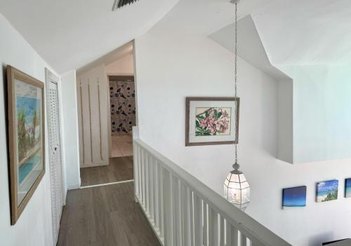 a hallway with white walls and a staircase with a pendant light at Sunset Cove - Vacation In Paradise! in Nassau