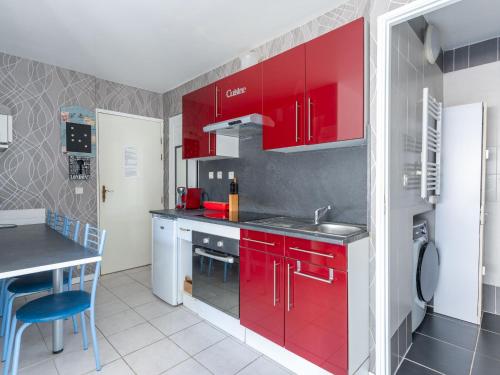 La cuisine est équipée de placards rouges, d'un évier et d'une table. dans l'établissement Appartement au Coeur de Mimizan Plage pour 4 Personnes, à Proximité des Commerces et Plages - FR-1-50-142, à Mimizan