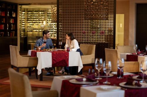a man and woman sitting at a table in a restaurant at The Ritz-Carlton, Bangalore in Bengaluru