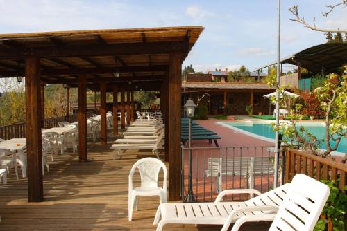 a row of white chairs on a deck next to a pool at Agriturismo Cameli in Certaldo