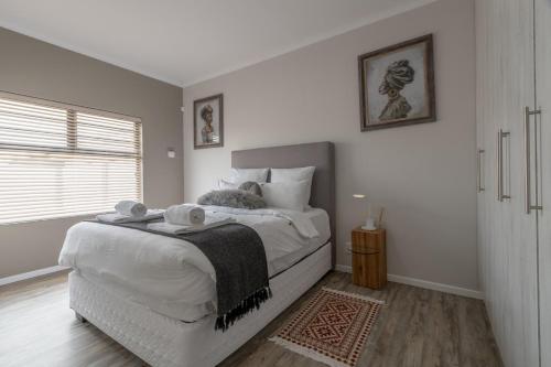 a white bedroom with a bed with towels on it at Nikita's Holiday Home - Walvis Bay in Walvis Bay