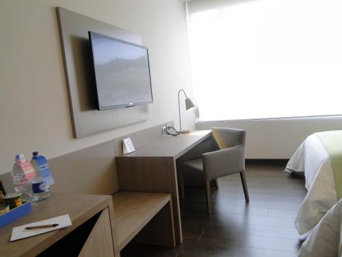 a hotel room with a desk and a tv on the wall at Hotel bh Usaquén in Bogotá