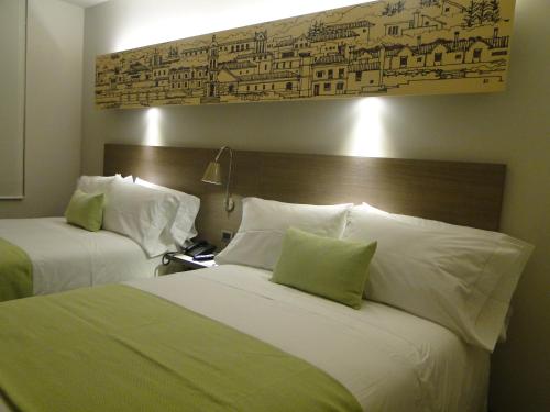 a hotel room with two beds with green and white pillows at Hotel bh Usaquén in Bogotá