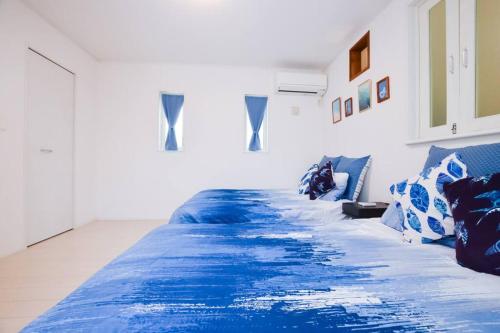 a bed with a blue comforter in a room at Villa Fukugi in Motobu