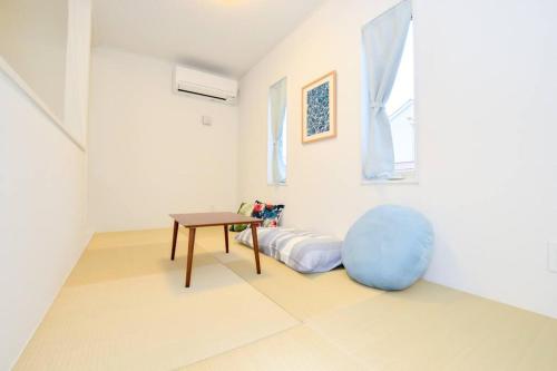 a white room with a table and a blue ottoman at Villa Fukugi in Motobu