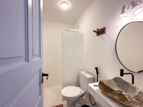 a white bathroom with a toilet and a mirror at Pousada Vilab in Arraial d'Ajuda