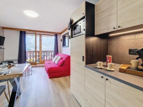 Il comprend une cuisine et un salon avec un canapé rouge. dans l'établissement Appartement rénové 2P, balcon sud-ouest, pied des pistes, parking, wifi, non fumeur. - FR-1-344-1215, aux Bruyères