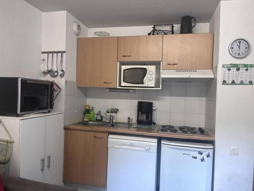 une petite cuisine avec un micro-ondes et une cuisinière dans l'établissement Charmant T2 à Cauterets avec parking et casier à skis - FR-1-812-29, à Cauterets