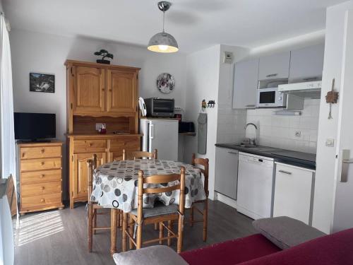 une cuisine avec une table et des chaises et une cuisine avec des appareils blancs dans l'établissement Charmant appartement à Cauterets avec balcon et parking privé - FR-1-812-30, à Cauterets