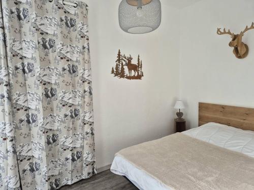 - une chambre avec un lit et un rideau avec un cerf sur le mur dans l'établissement T2 au Centre, Proche Télécabine et Services à Cauterets - FR-1-234-329, à Cauterets