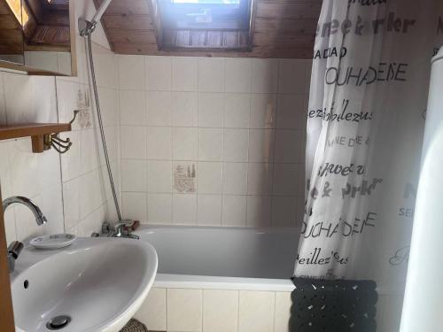 La salle de bains est pourvue d'un lavabo et d'une baignoire avec rideau de douche. dans l'établissement Chalet confortable à Cauterets avec parking et balcon - FR-1-812-10, à Cauterets