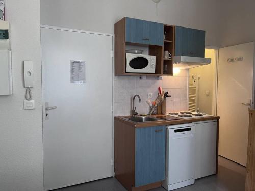 Elle comprend une petite cuisine avec des placards bleus et un réfrigérateur blanc. dans l'établissement Doux séjour familial à Cauterets - FR-1-812-55, à Cauterets