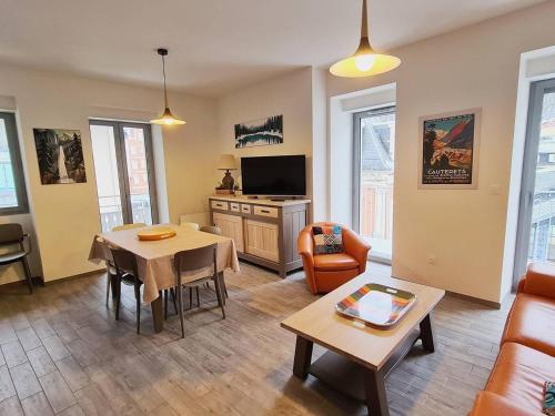 un salon avec un canapé, une table et une télévision dans l'établissement Appartement rénové 3 ch, centre-ville Cauterets - FR-1-812-39, à Cauterets