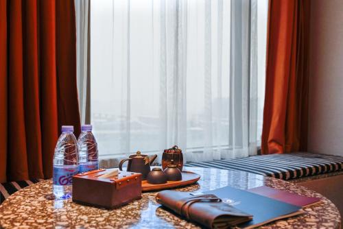 a table with a laptop and water bottles on it at Arthur Hotel Liwan COCO Park Dongsha Metro Guangzhou-24H Coffee & Low Tea & Free Shuttle Bus For Canton Fair By Paco in Guangzhou