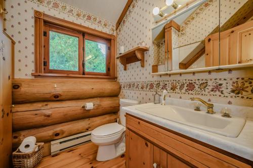 a bathroom with a sink and a toilet and a window at Massive Rustic Waterfront Log Cabin in Stokes Bay
