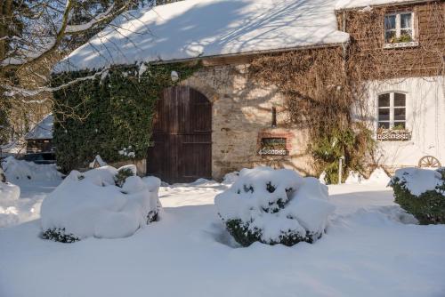 a stone house with a wooden door in the snow at Ferienwohnung Kutscherstube in Altenbeken