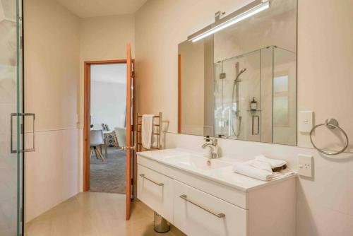 a white bathroom with a sink and a shower at Breath Taking Views of Lake Taupo in Taupo