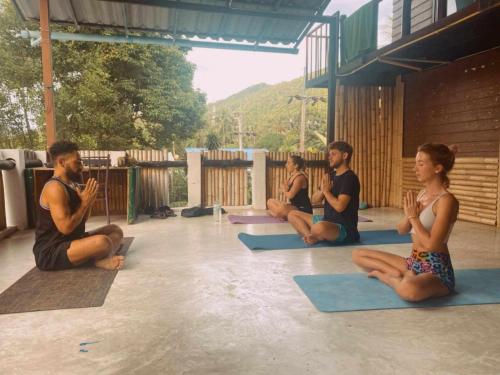 un grupo de personas sentadas en una clase de yoga en MoovInn Garden Guesthouse, en Ko Tao
