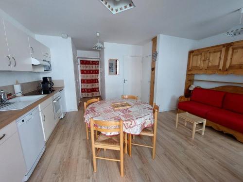 une petite cuisine avec une table et un canapé rouge dans l'établissement Charmant studio à Cauterets avec balcon et couchages pour 4 personnes - FR-1-812-62, à Cauterets
