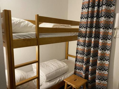 - une chambre avec 2 lits superposés et un rideau dans l'établissement Appartement cosy Cauterets, télécabine, parking, Wi-Fi, 4 pers - FR-1-812-79, à Cauterets