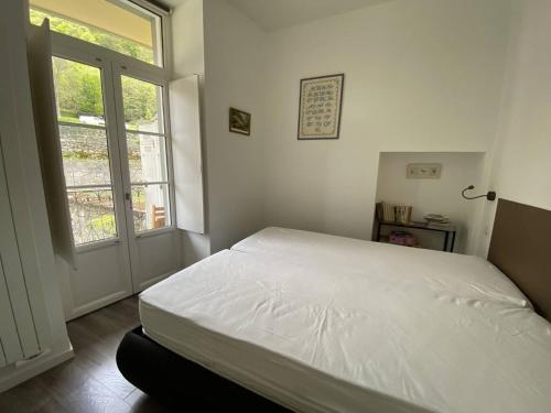 un lit blanc dans une chambre avec une fenêtre dans l'établissement Appartement à Cauterets, proche télécabines, 4 pers, balcon vue montagne - FR-1-812-76, à Cauterets