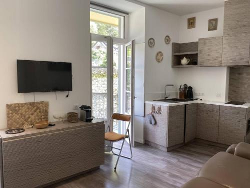 Il comprend un salon doté d'une cuisine avec une table et une télévision. dans l'établissement Appartement à Cauterets, proche télécabines, 4 pers, balcon vue montagne - FR-1-812-76, à Cauterets