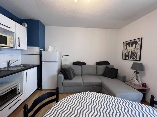 un petit salon avec un canapé et une cuisine dans l'établissement Appartement cosy à Cauterets avec terrasse et local à ski - FR-1-812-84, à Cauterets