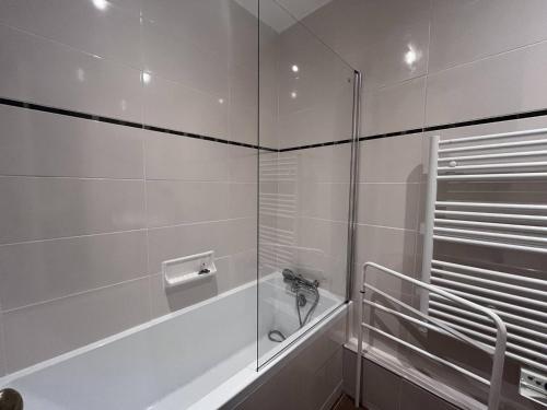 La salle de bains blanche est pourvue d'une douche et d'une baignoire. dans l'établissement Appartement cosy 6 pers, 2 chambres, Cauterets - FR-1-812-88, à Cauterets