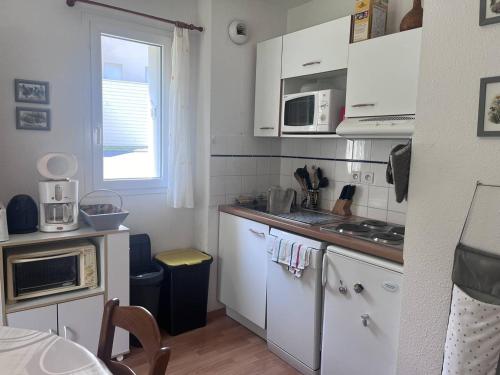 Elle comprend une petite cuisine avec des placards blancs et une fenêtre. dans l'établissement Charmant appartement avec terrasse et parking privé à Cauterets - FR-1-812-110, à Cauterets