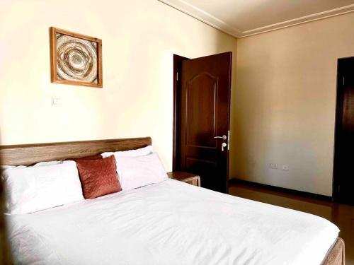 a bedroom with a white bed with a wooden headboard at Aspen Luxury Villa in Accra
