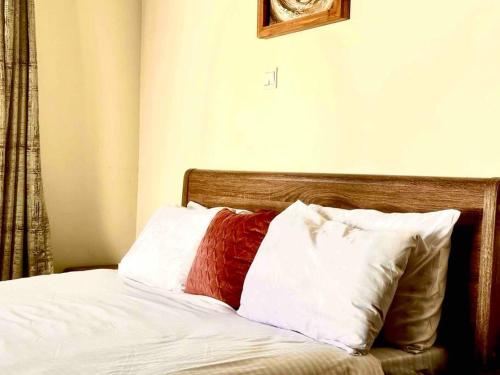 a bed with white and red pillows on it at Aspen Luxury Villa in Accra
