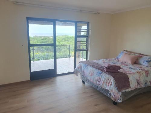 ein Schlafzimmer mit einem Bett und einer Glasschiebetür in der Unterkunft 36 Steps to Beach Sand in Gqeberha