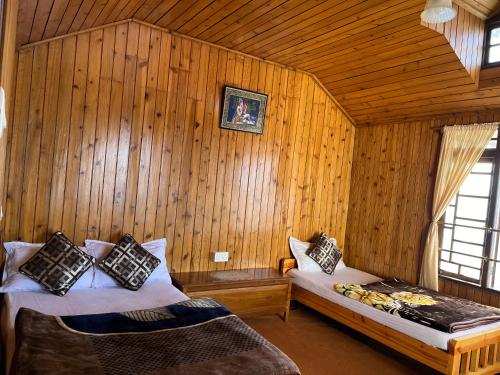 1 dormitorio con 2 camas en una pared de madera en Eagle's Nest Homestay, en Darjeeling