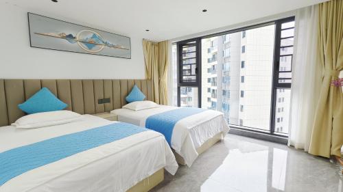 Dos camas en una habitación con una gran ventana. en Zhangjiajie Qingfeng B&B West Station Branch, en Zhangjiajie